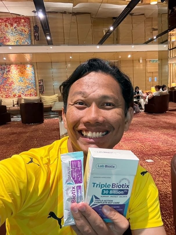 Ustaz Yaakud Yusra, pendakwah, tersenyum sambil memegang kotak dan sachet TripleBiotix