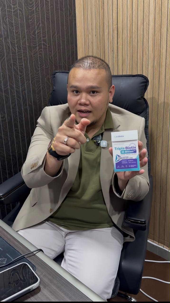 Dr Wan, doktor pakar, duduk di pejabat sambil memegang kotak TripleBiotix dan menuding ke kamera